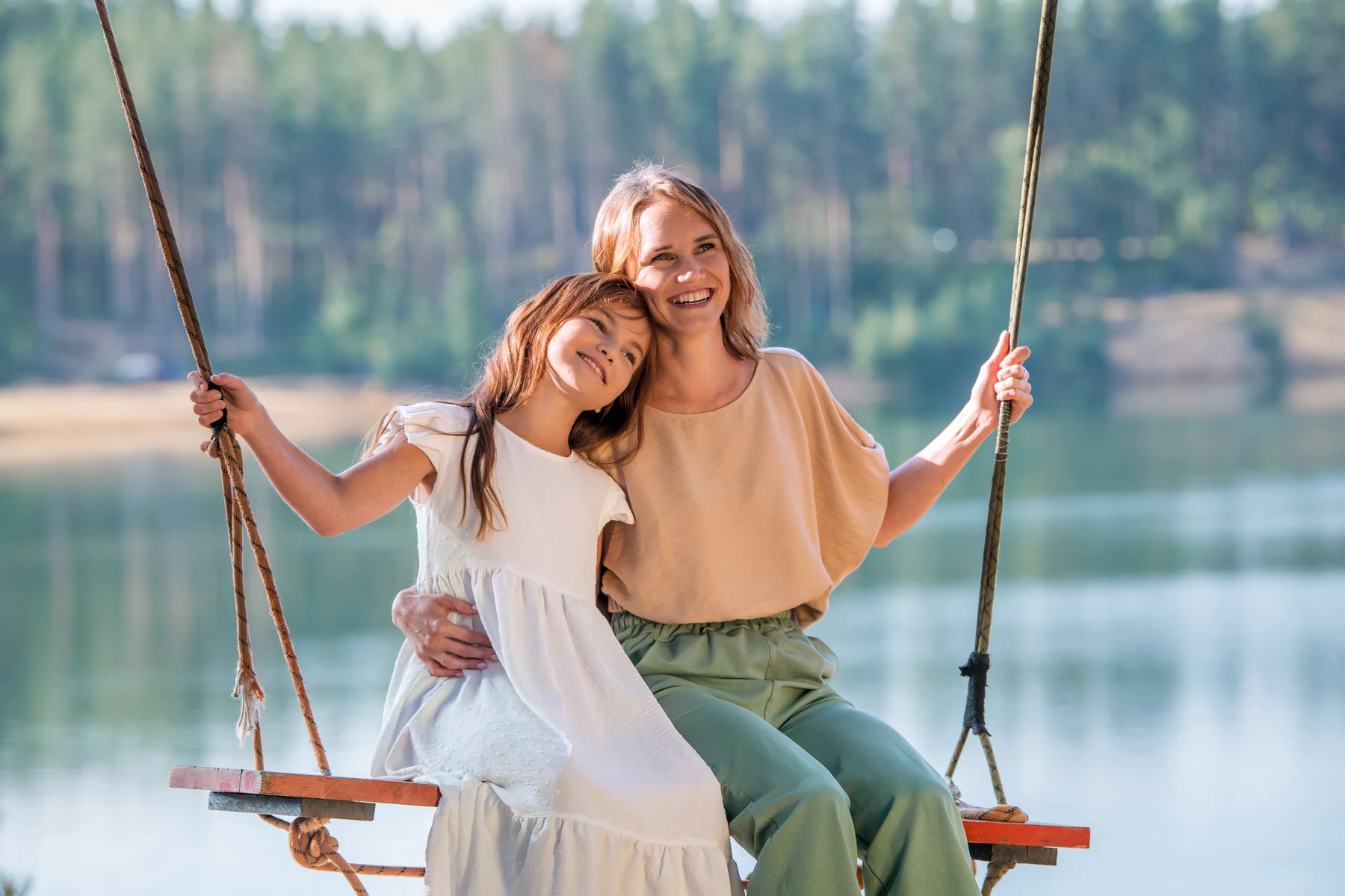 A parent and child smiling together on a swing for Dental Insurance.